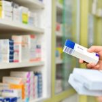 Pharmacist holding medicine box in pharmacy drugstore.