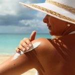 Woman applying Suntan Lotion at the beach