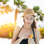 beautiful woman smears face sunscreen at the beach for sun protection