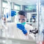 Scientist-pouring-a-reagent-into-a-measuring-cylinder-Stock-image.jpg